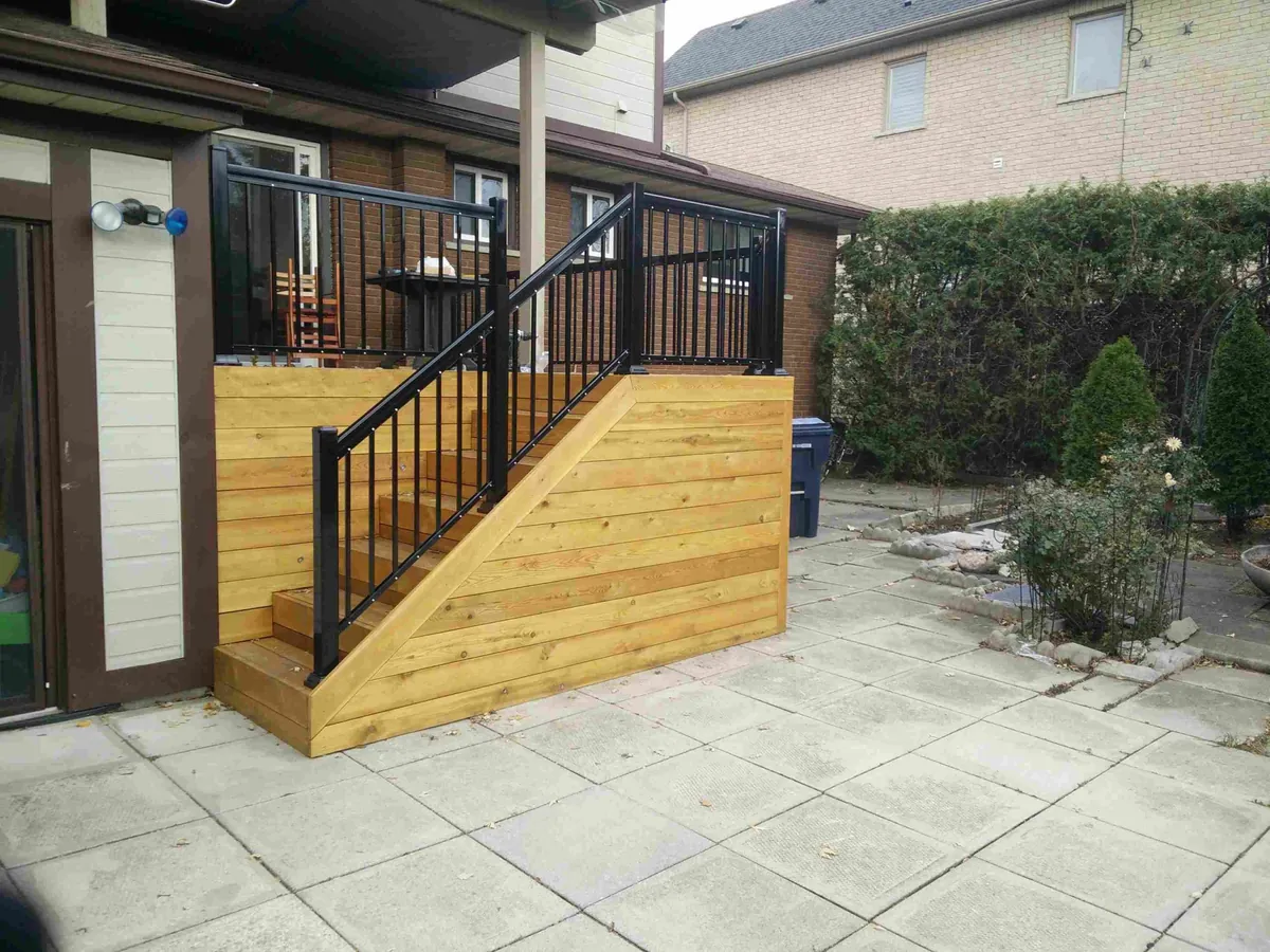 Wood deck stairs with black aluminum railing built beside a house wall in Newmarket