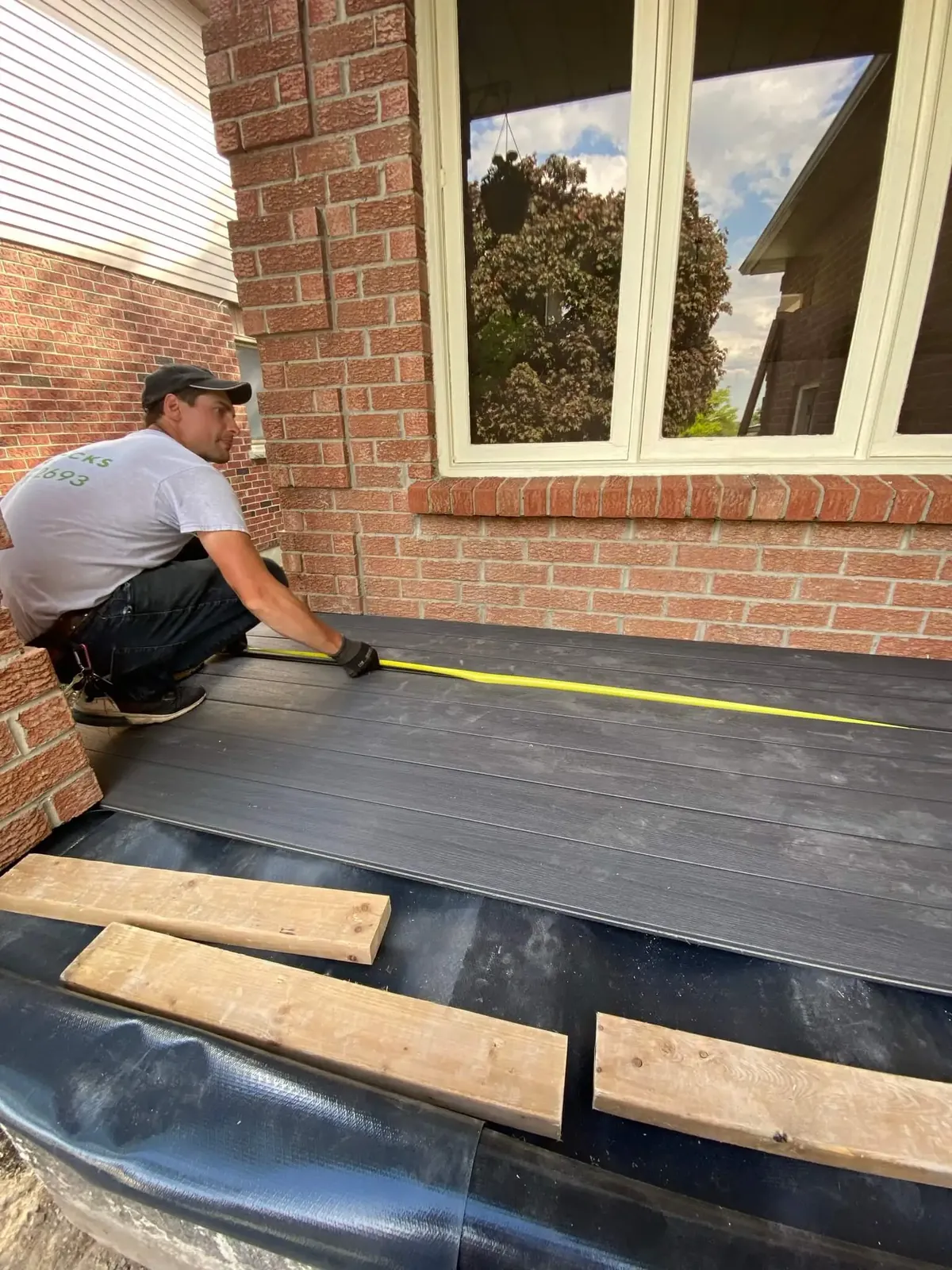XP Decking installer measuring composite boards during deck installation at Ontario home