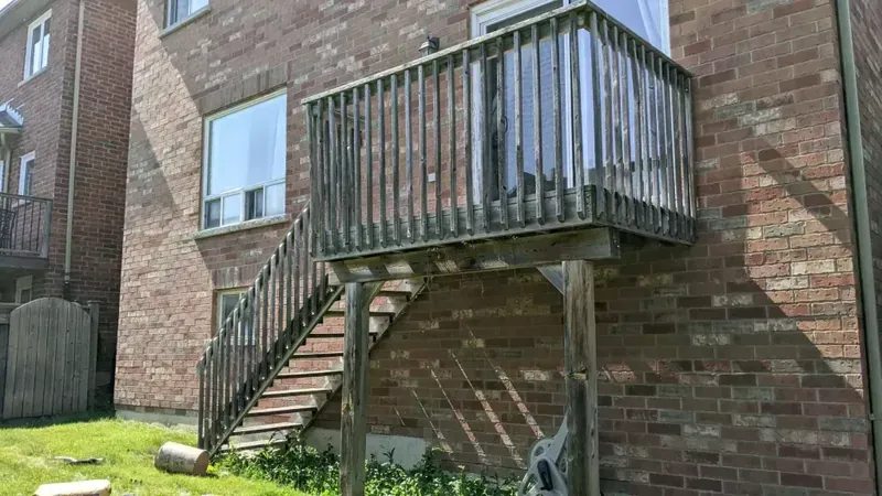 Weathered second-storey wood deck and railing before repair