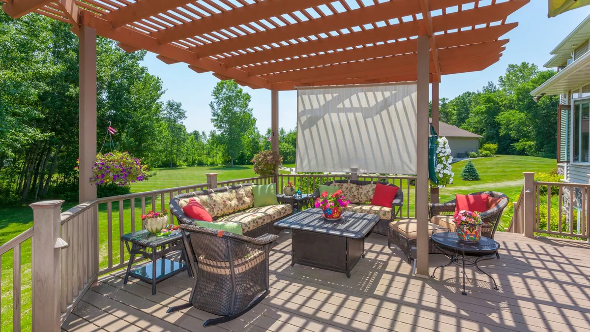 Beautiful backyard deck with pergola, outdoor seating, flowers, and clean wood surface after spring deck maintenance.