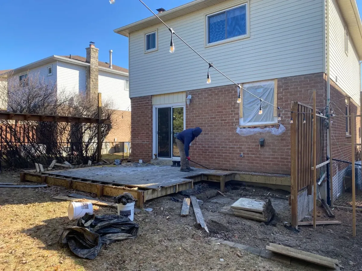 Worker removing old pressure treated wood deck during demolition in Newmarket Ontario backyard