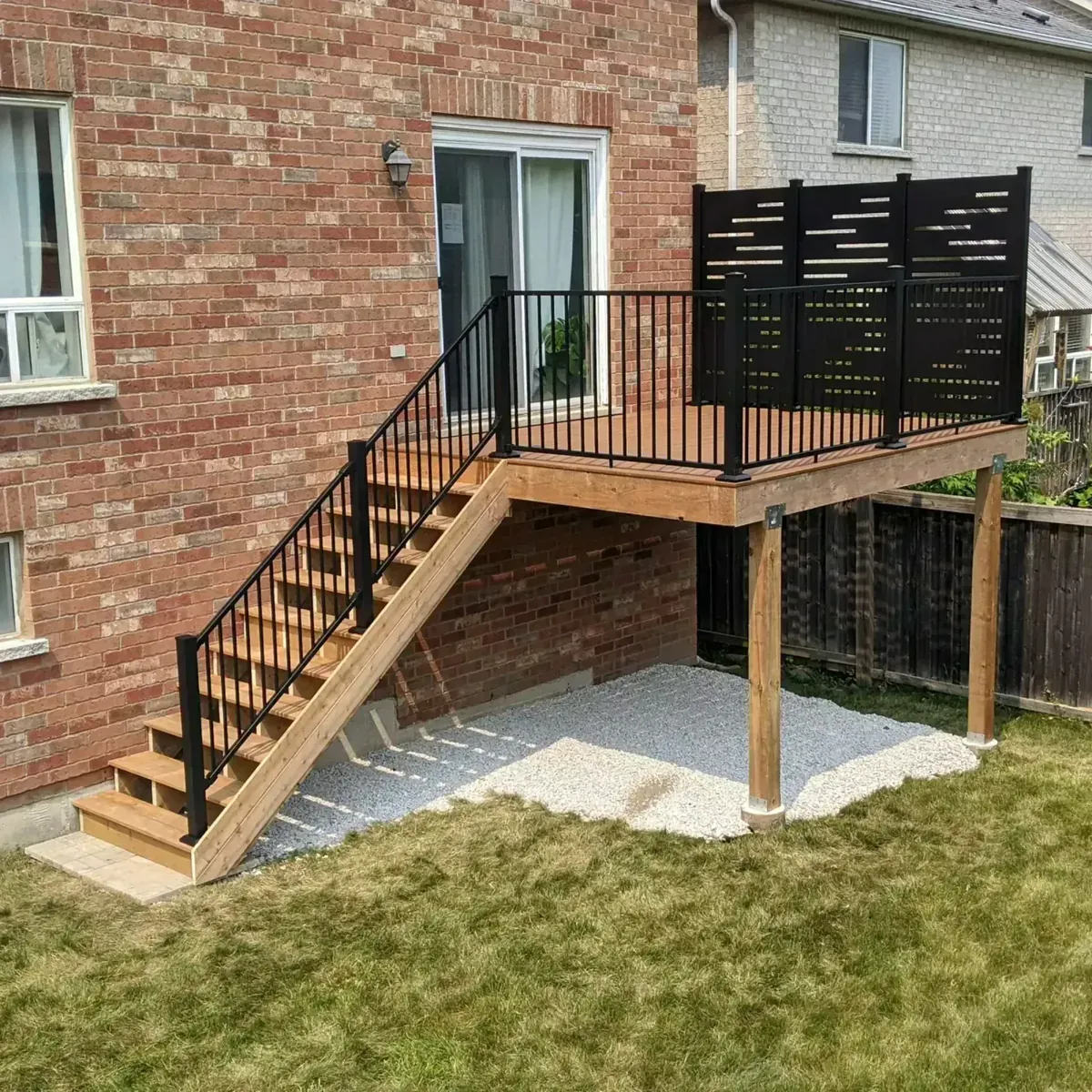 Modern wood deck with black metal railings and privacy screen on a brick house