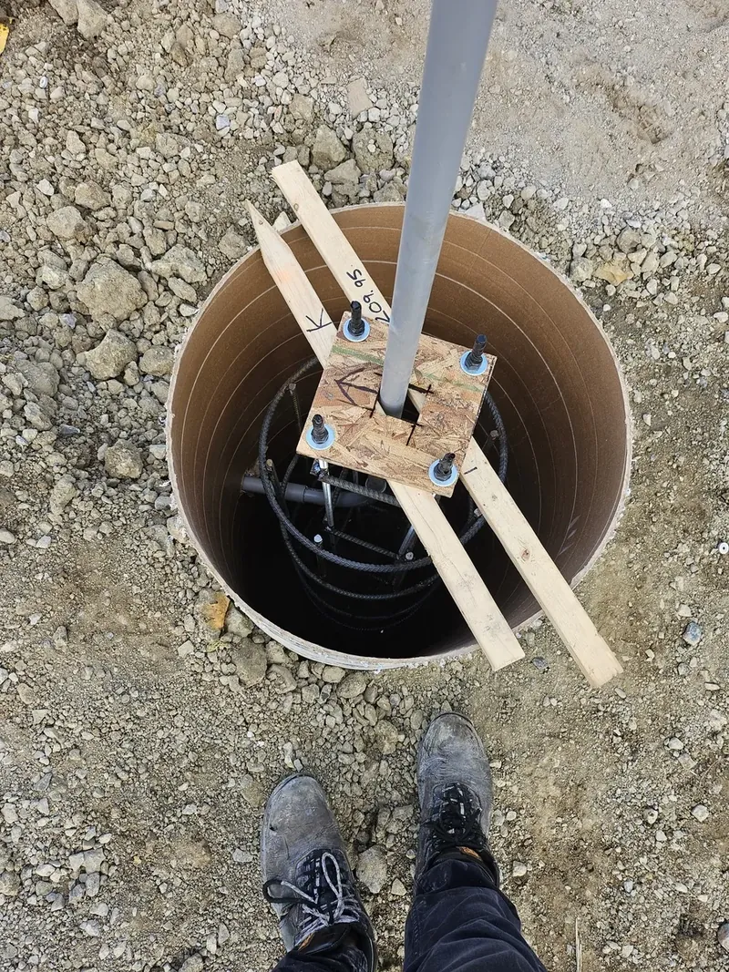 Post hole augered below the frost line with a bracket set on temporary formwork, ready for a pergola footing