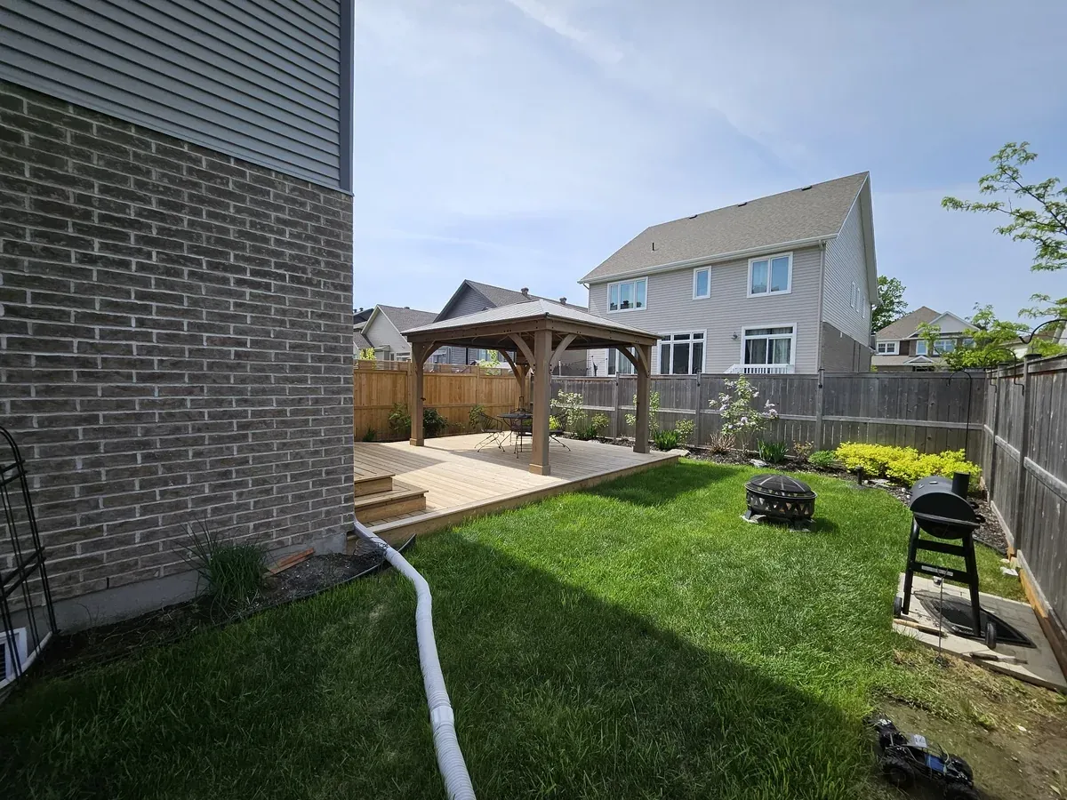 Gazebo and adjoining deck seen from the corner of the house, with a fire bowl and lawn in the foreground