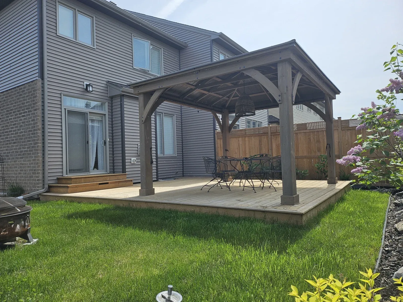 Timber-frame gazebo with a hip roof built on a low cedar deck pad in a Newmarket back garden, with patio furniture underneath