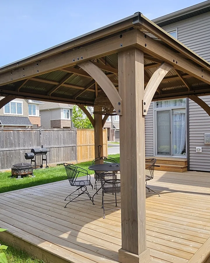 Heavy cedar gazebo post with a curved knee brace and visible joinery, carrying the roof beam