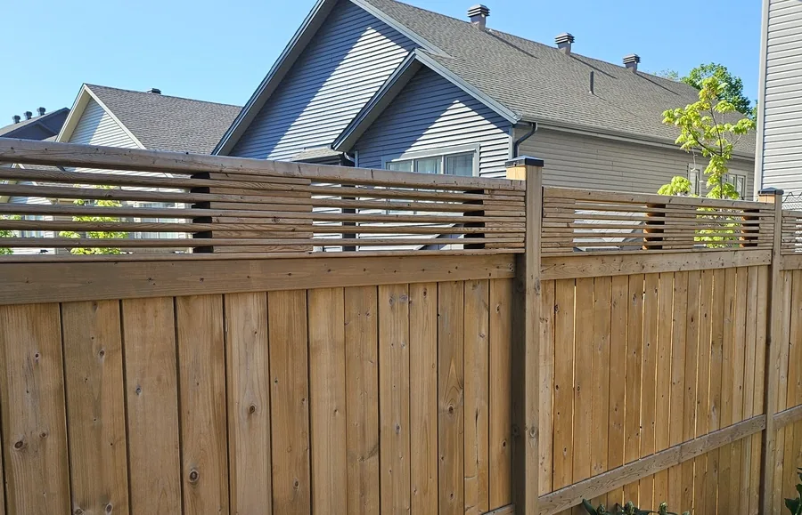 Open horizontal slat topper above a solid pressure-treated fence, adding height without a solid-wall look