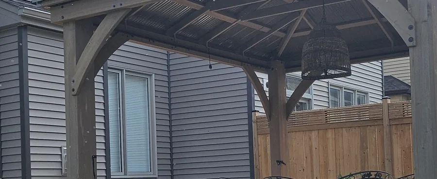 Underside of a gazebo roof showing ribbed steel roofing panels spanning the rafters