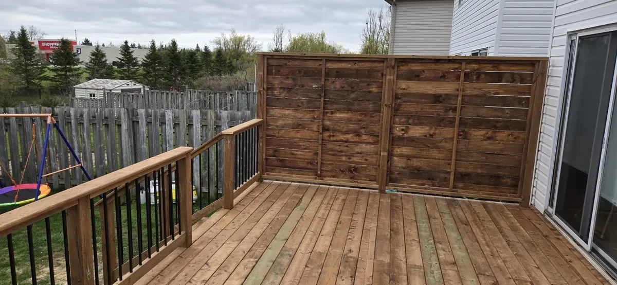 Privacy screen panels and black aluminium deck railing around a pressure-treated deck in Newmarket