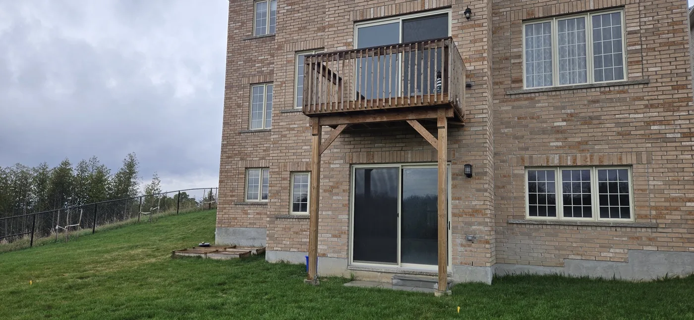 Rebuilt wood balcony with railing on the rear of a brick low-rise building