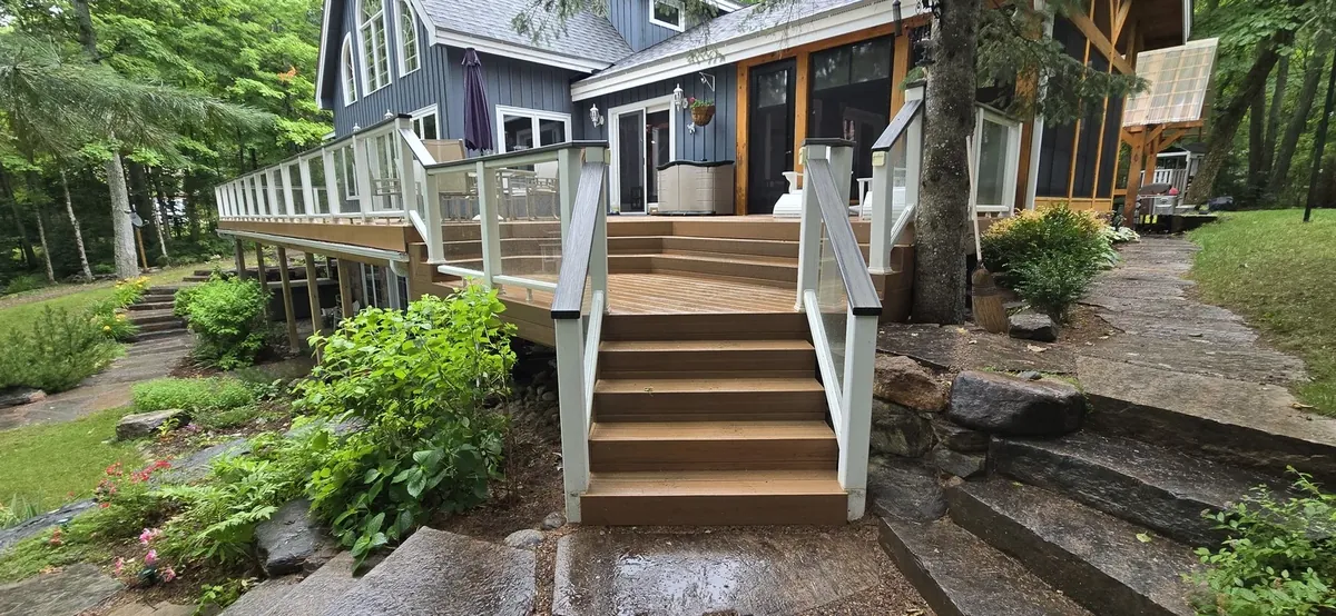 Cedar deck and stairs with white railings on a stone-clad home, built by XP Decking