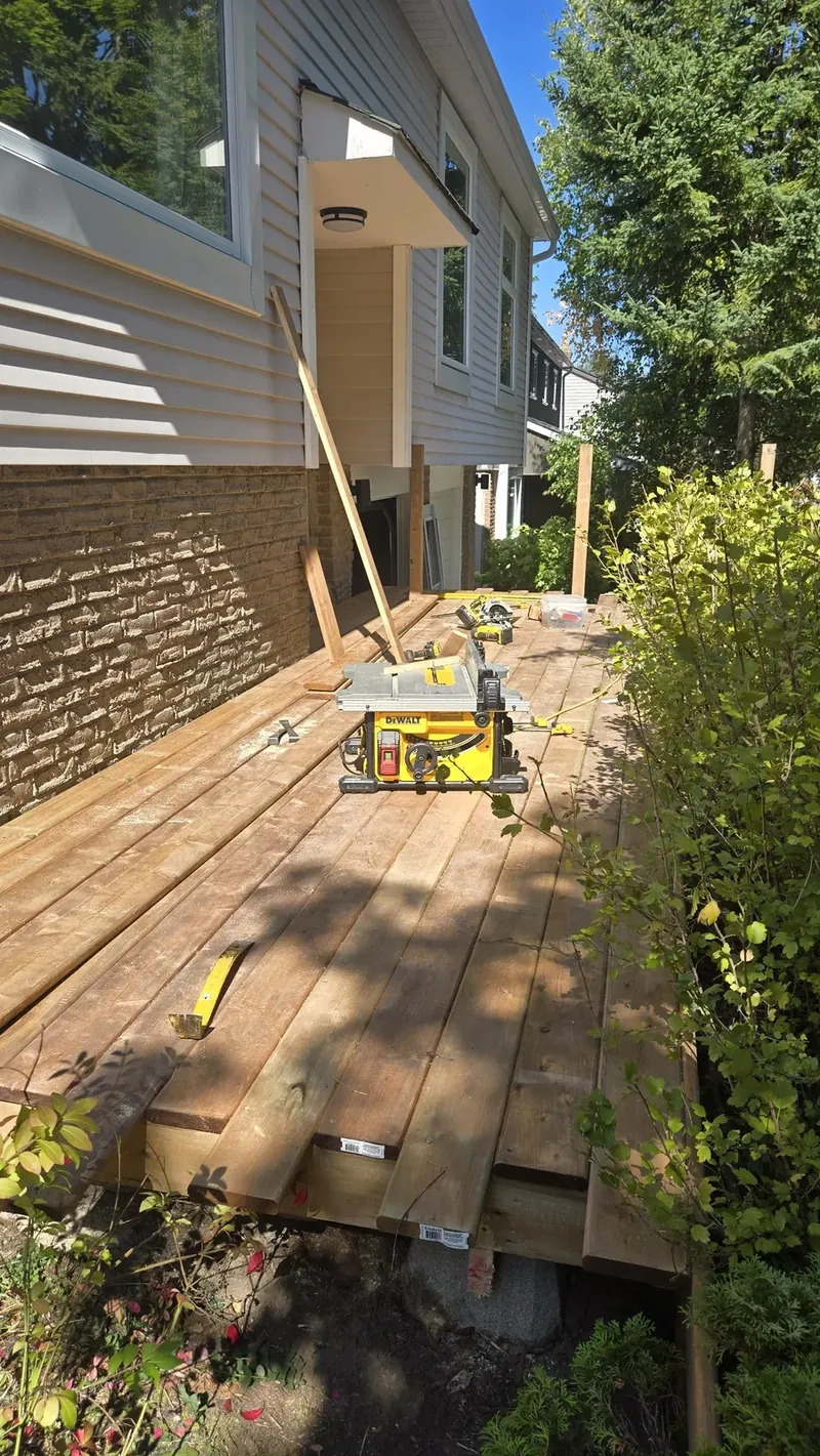 Mitre saw and tools on weathered deck boards during a repair, with new lumber ready