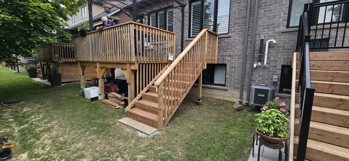 New pressure-treated deck with stairs and railings on a brick house, built by XP Decking
