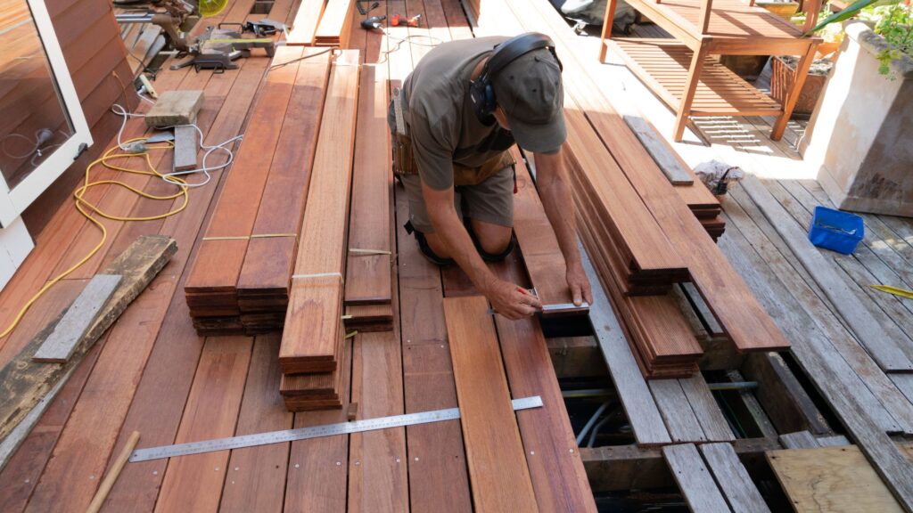 Contractor repairing damaged wooden boards to fix common deck problems in Ontario homes, addressing rot, cracks, and structural issues.